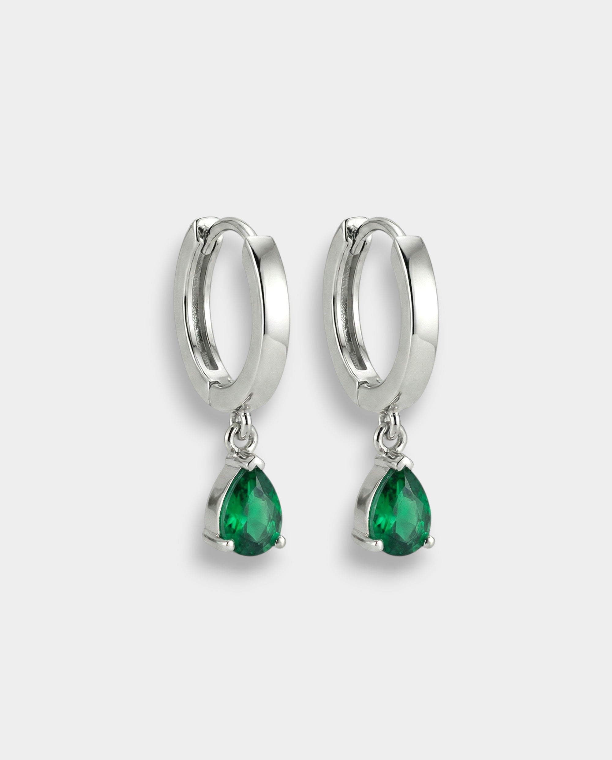 White gold hoop earrings with emeralds on a white background