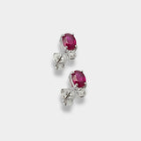 Pair of white-gold earrings with rubies on a light gray background