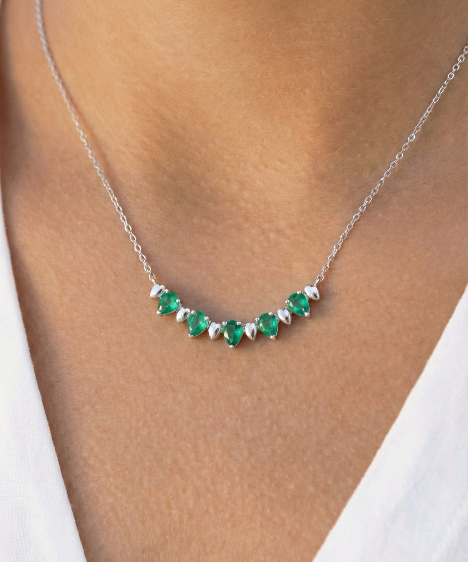 White gold and pear-cut emerald alternate necklace on a model's neck