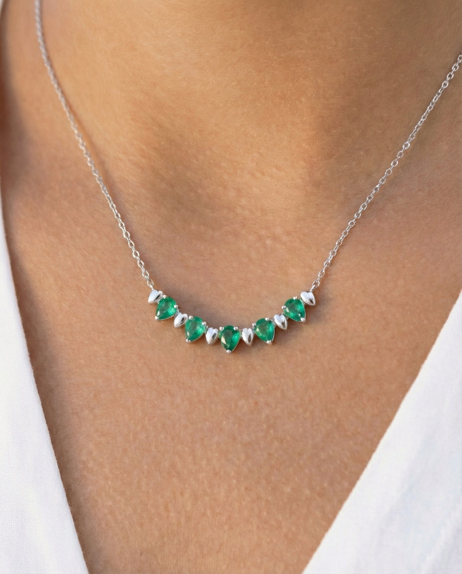 White gold and pear-cut emerald alternate necklace on a model's neck