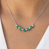 White gold and pear-cut emerald alternate necklace on a model's neck