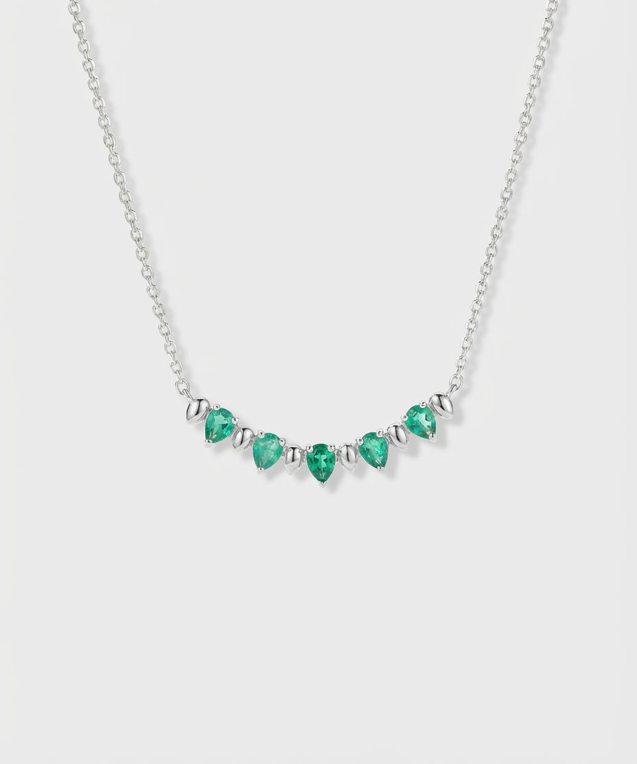 Necklace with pear-cut emeralds and white gold on a white background