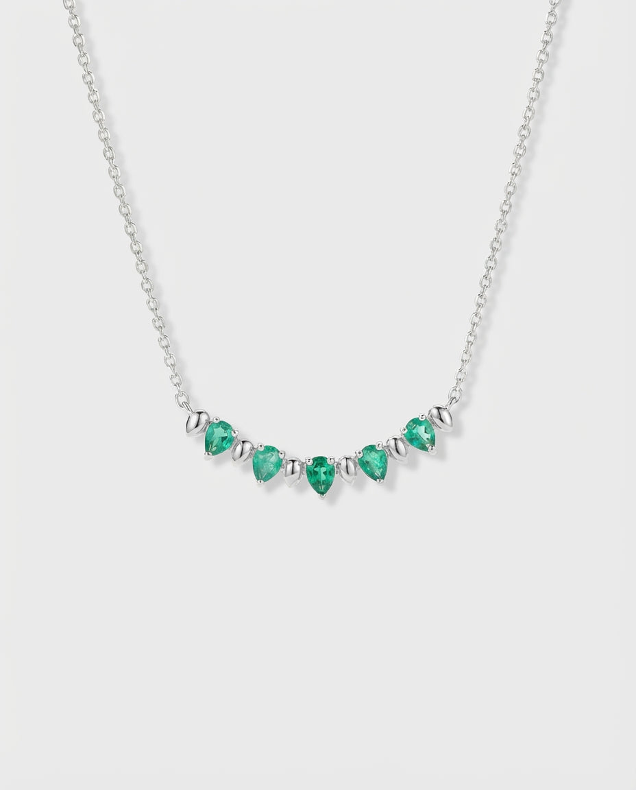 Necklace with pear-cut emeralds and white gold on a white background