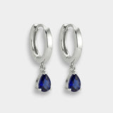 White gold hoop earrings with blue teardrop sapphires on a white background