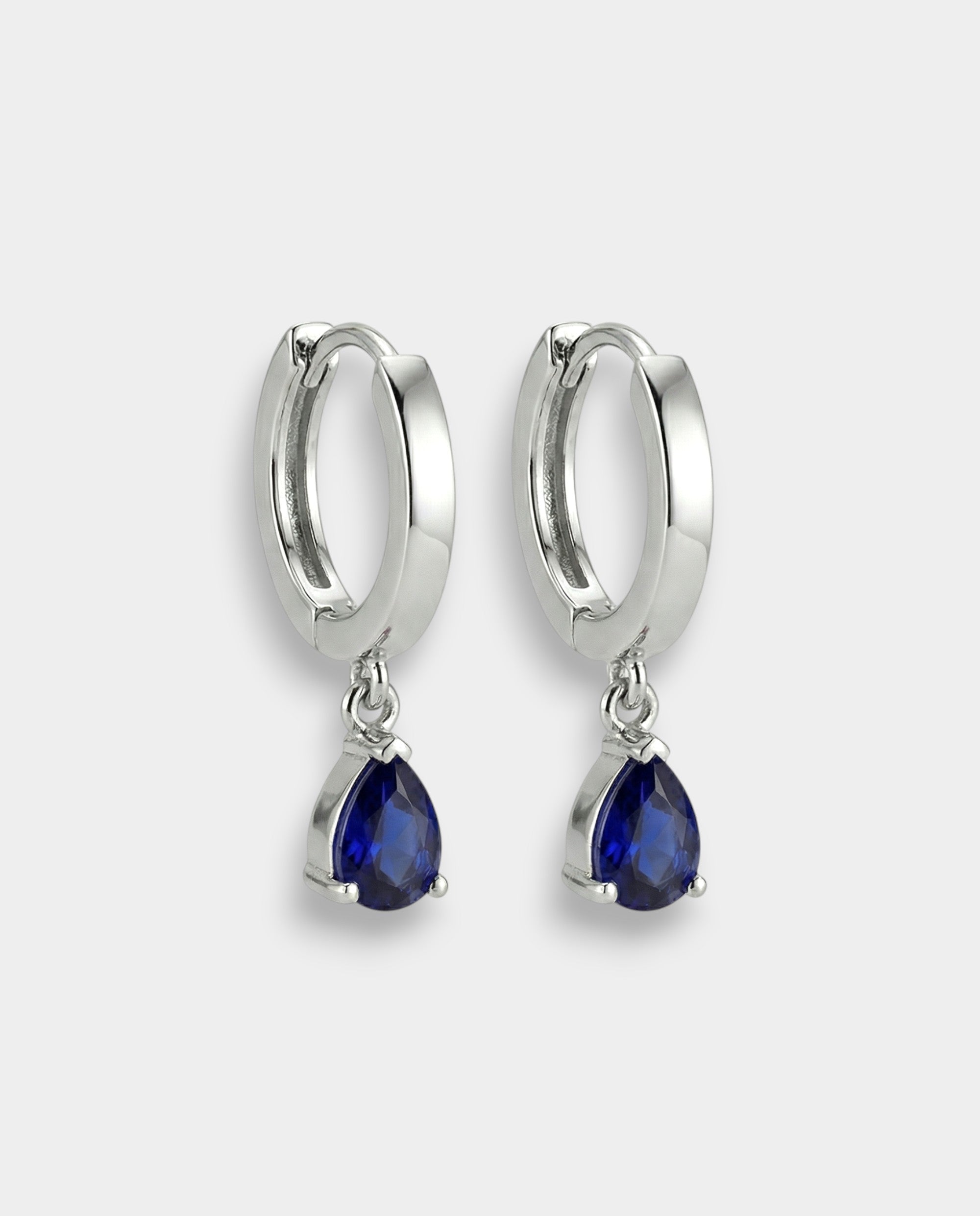 White gold hoop earrings with blue teardrop sapphires on a white background