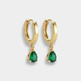 Gold hoop earrings with pear-cut emeralds on a white background