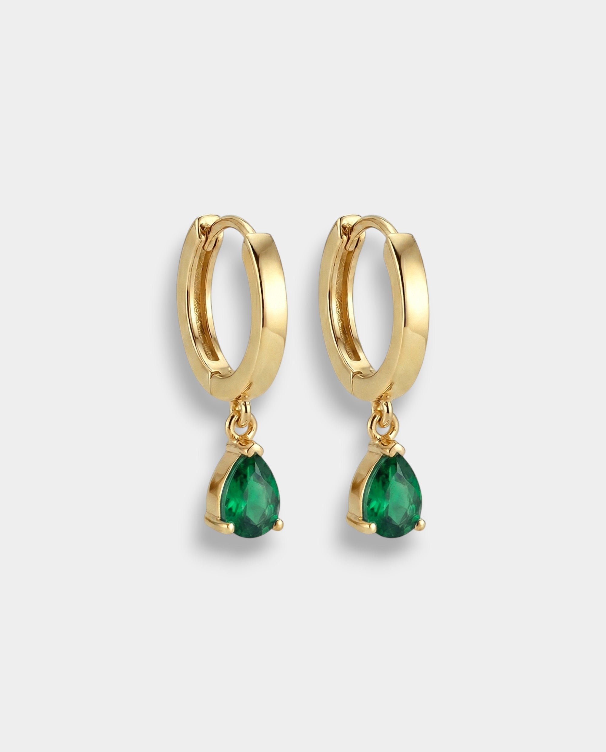 Gold hoop earrings with pear-cut emeralds on a white background